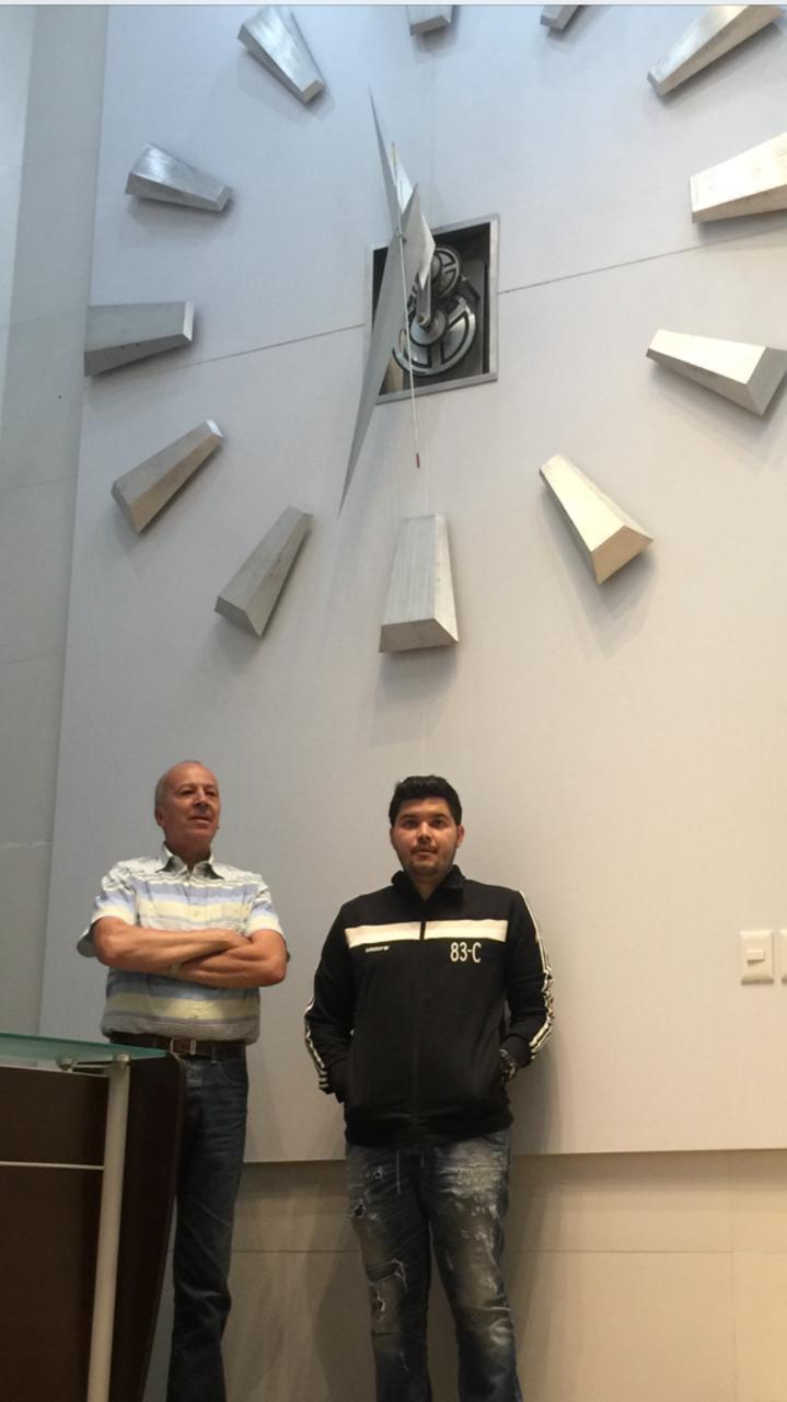 Reloj monumental con índices tridimensionales en muro de doble altura