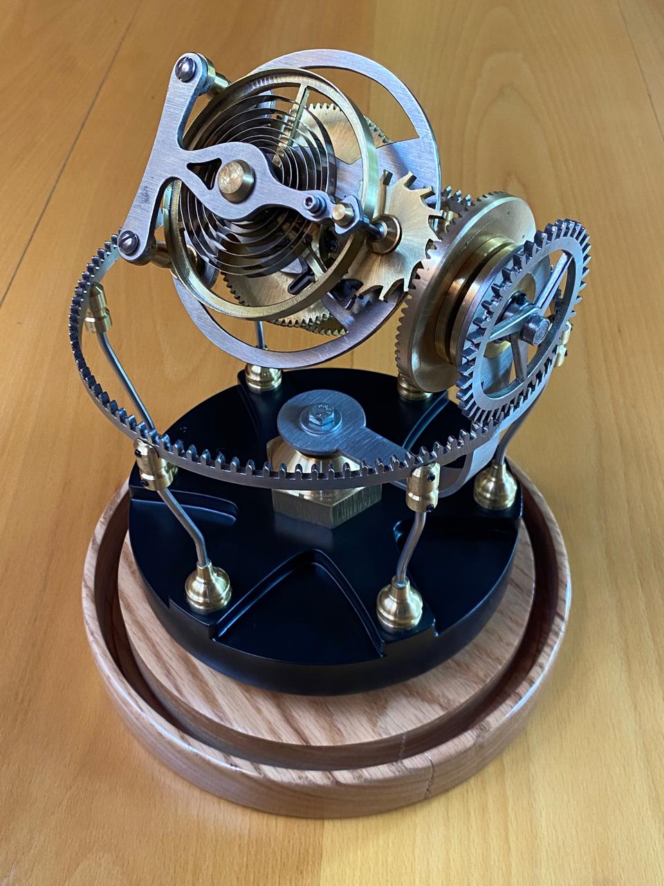 Tourbillon Triax: jaula con espiral y engranes sobre base negra y madera